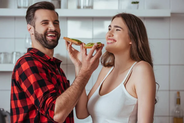 Cheerful Young Couple Laughing While Holding Toasts Fresh Avocado — Stock Photo, Image