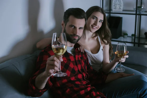 Feliz Jovem Casal Olhando Para Câmera Enquanto Sentado Sofá Segurando — Fotografia de Stock