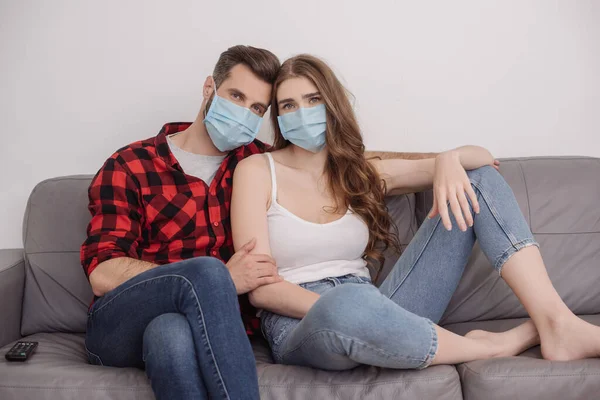 Depressed Young Couple Medical Masks Sitting Sofa Looking Camera — Stock Photo, Image