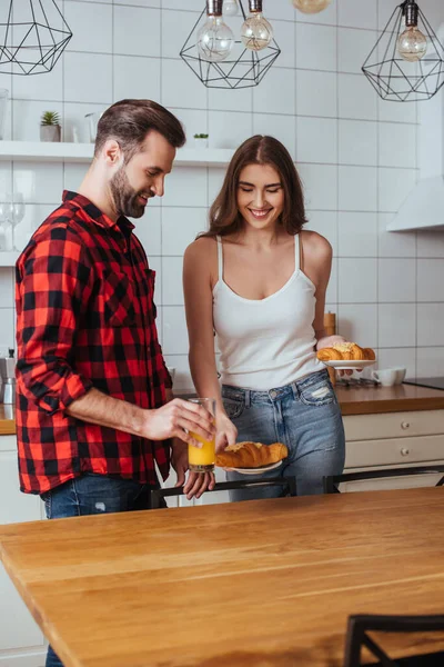 Feliz Casal Jovem Segurando Pratos Com Croissants Deliciosos Vidro Suco — Fotografia de Stock