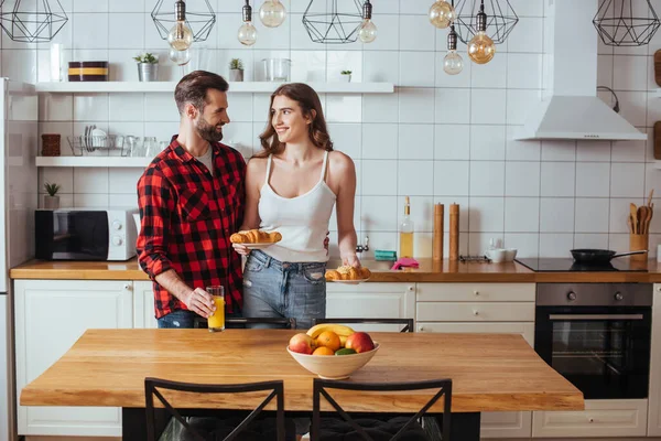 Chica Feliz Sosteniendo Platos Con Croissants Mientras Mira Sonriente Novio — Foto de Stock