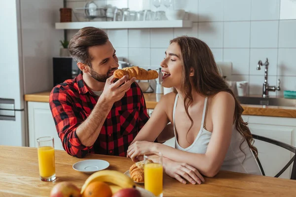 Homem Feliz Alimentando Namorada Bonita Com Delicioso Croissant Perto Suco — Fotografia de Stock