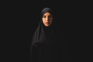 Beautiful muslim woman looking at camera isolated on black  clipart