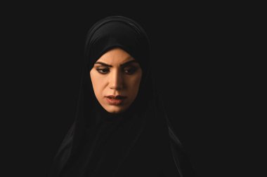 Sad muslim woman looking away isolated on black  clipart