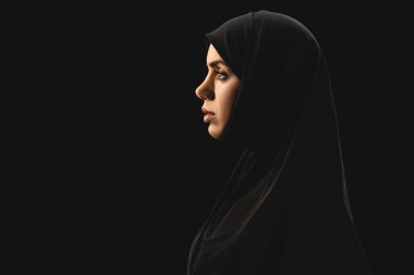 Siyah üzerine izole edilmiş tesettürlü güzel Müslüman kadının yan görüntüsü 