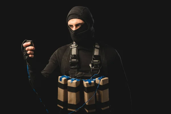Muslim terrorist in balaclava holding detonator of explosive belt isolated on black