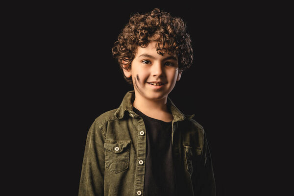 Улыбающийся мусульманский мальчик с грязным лицом, смотрящий в камеру, изолированную на черном
 