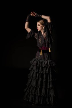 Kafasının üstünde elleri olan çekici bir dansçı. Siyah üzerine izole edilmiş flamenko dansı yapıyor.