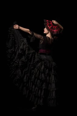 young and beautiful dancer holding fan while dancing flamenco isolated on black  clipart