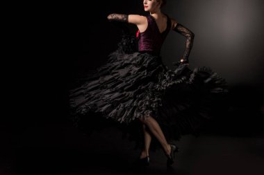 cropped view of flamenco dancer in dress and shoes dancing on black  clipart