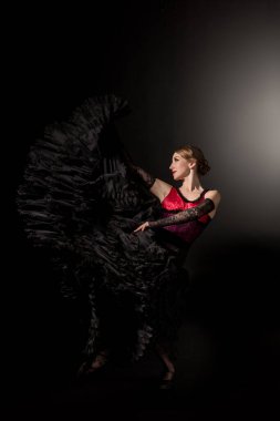 Mutlu ve genç flamenko dansçısı siyah elbiseyle dans ediyor. 