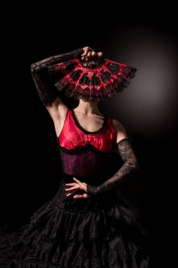 Genç flamenko dansçısı siyah yelpazeyle yüzünü kapatıyor