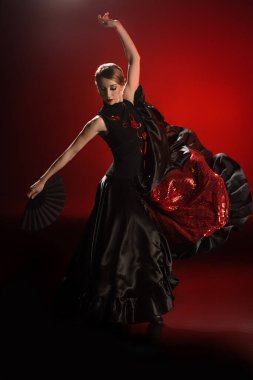 Kırmızı üzerinde dans ederken elinde yelpaze tutan güzel flamenko dansçısı 