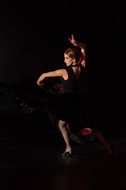 Siyah üzerinde flamenko yapan genç bir dansçı. 