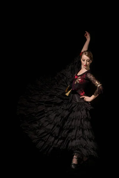 elegant flamenco dancer with hand on hip dancing isolated on black