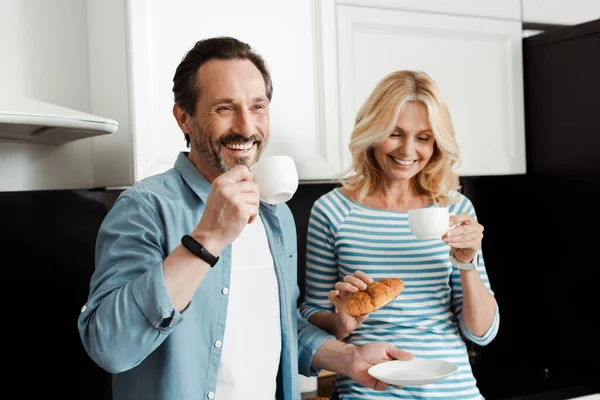 Cheerful Middle Aged Couple Drinking Coffee Holding Croissant Kitchen — Stock Photo, Image