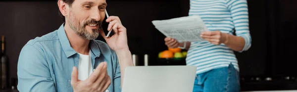 Panoramische Oriëntatie Van Lachende Man Praten Smartphone Buurt Van Laptop — Stockfoto