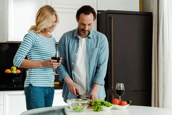 Foco Seletivo Mulher Sorridente Segurando Copo Vinho Perto Marido Cozinhando — Fotografia de Stock