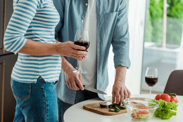 Vista Recortada Mujer Sosteniendo Vaso Vino Cerca Hombre Cortando Verduras — Foto de Stock