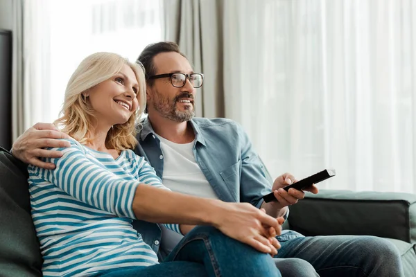 Selective Focus Man Holding Remote Controller Embracing Smiling Wife Couch — Stock Photo, Image