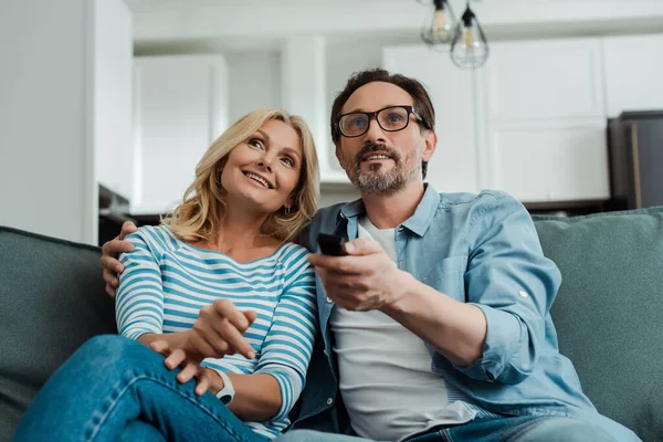 笑顔成熟したカップルの選択的な焦点テレビを見ます上のソファ — ストック写真