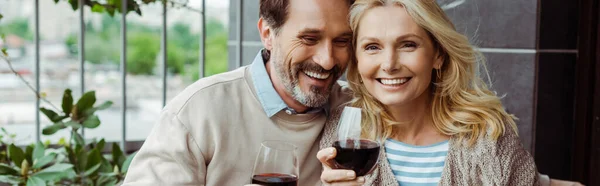 テラスでワインのガラスと笑顔の妻を受け入れる男のパノラマ作物 — ストック写真