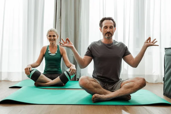 Mature Man Meditating Fitness Mat Smiling Wife Living Room — Stock Photo, Image