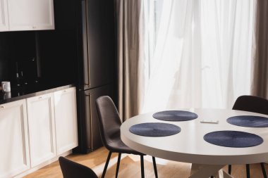 Modern sandalyelerin yanındaki yemek masasında akıllı telefon. 