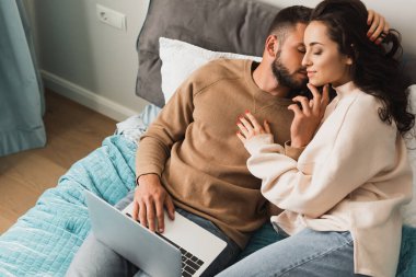 Yatak odasında bilgisayarın yanında güzel bir kızı öpen sakallı bir serbest yazar. 