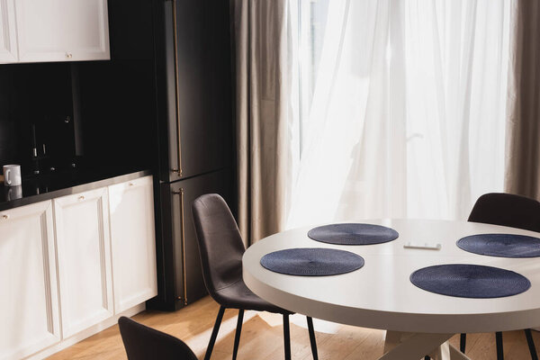 смартфон на обеденном столе возле современных стульев
 