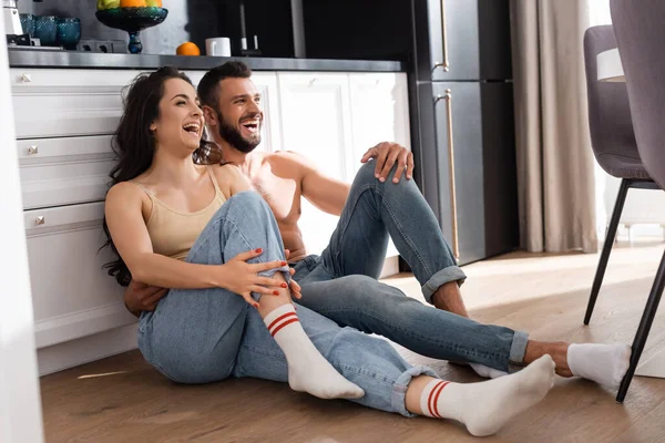 Gelukkig Vrouw Shirtloze Man Lachen Terwijl Zitten Vloer — Stockfoto