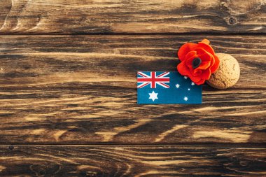 top view of australian flag near artificial flower and cookie on wooden surface  clipart