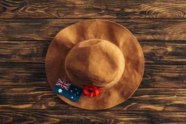 Yapay çiçeğin üst görüntüsü, keçeli şapka ve tahta yüzeyde Avustralya bayrağı, Anzak Günü konsepti 