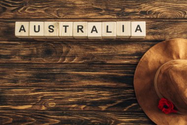 top view of artificial flower, felt hat and cubes with australia lettering on wooden surface, anzac day concept  clipart