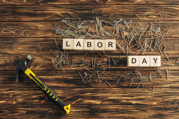 верхний вид металлических гвоздей и молотка возле кубов с надписью трудового дня на деревянной поверхности
