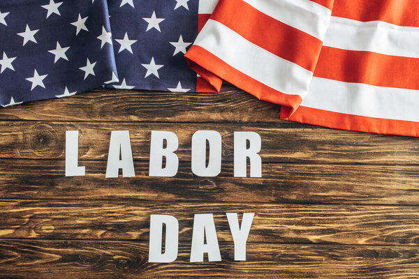 top view of american flag with stars and stripes near labor day lettering on wooden surface 