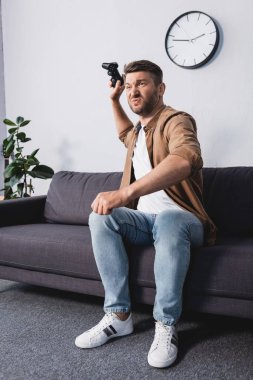 KYIV, UKRAINE - 9 Haziran 2020: Evdeki kanepede otururken joystick atan kızgın adam
