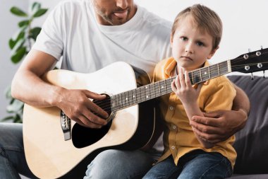 Baba, oğluna akustik gitar çalmayı öğretiyor.