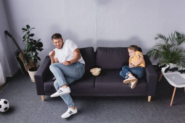 Korkmuş, endişeli baba ve oğul evdeki kanepede televizyon izliyorlar.