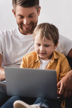 Baba ve oğlunun evde dizüstü bilgisayarı birlikte kullanmasının seçici odağı.