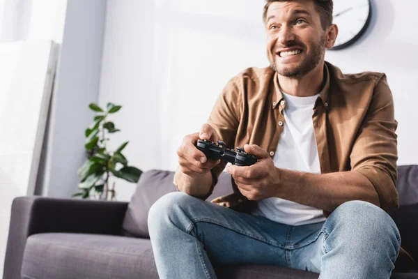 Kyiv Ukraine 2020年6月9日 興奮した男が自宅でソファにジョイスティックでビデオゲームをプレイ — ストック写真