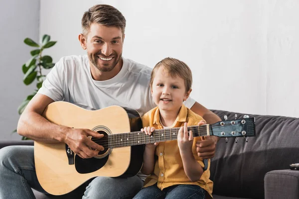 Счастливый Отец Учить Веселый Сын Играть Акустической Гитаре — стоковое фото