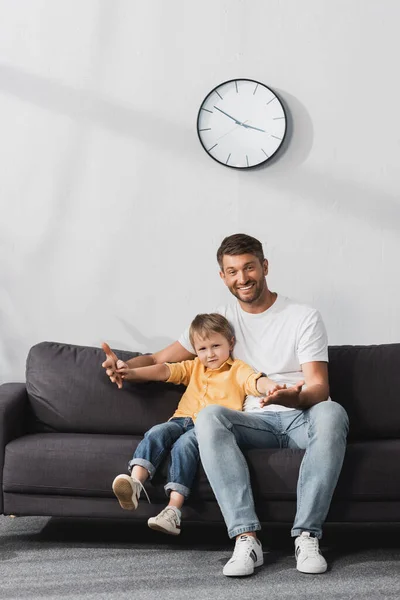 Happy Father Holding Hands Adorable Son While Sitting Sofa Looking — Stock Photo, Image