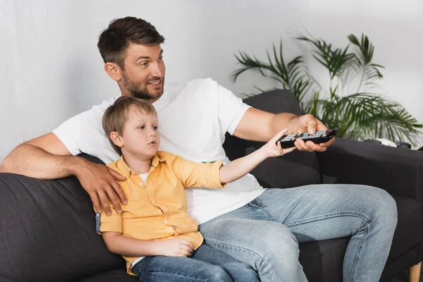 Smiling Father Bored Son Clicking Channels Remote Controller While Watching — Stock Photo, Image