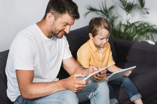Enfoque Selectivo Padre Sonriente Hijo Atento Utilizando Tabletas Digitales Casa —  Fotos de Stock