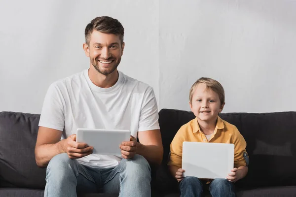 Cheerful Father Son Smiling Camera While Sitting Sofa Using Digital — Stock Photo, Image