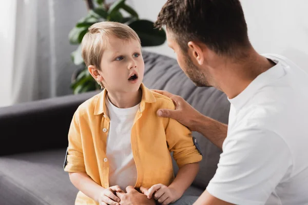 Father Touching Shoulder Socked Son While Talking Him Sofa — Stock Photo, Image