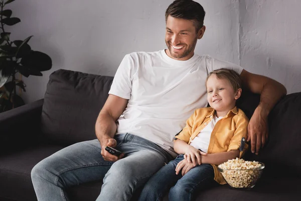 Sonriente Padre Sosteniendo Control Remoto Televisión Sonriente Hijo Cerca Tazón —  Fotos de Stock