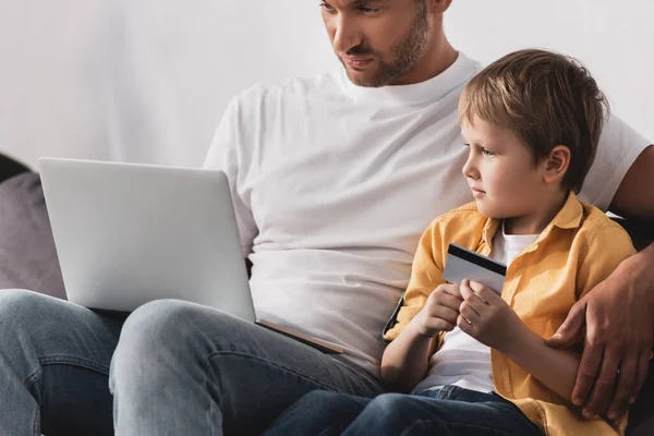 Koncentrált Apa Használja Laptop Míg Imádnivaló Fiú Kezében Hitelkártya — Stock Fotó