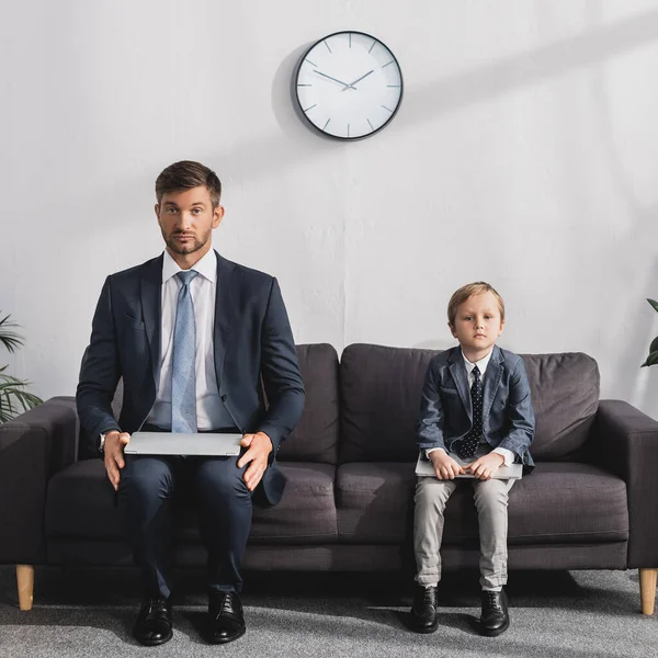 Empresário Sério Seu Filho Desgaste Formal Sentado Com Laptops Sofá — Fotografia de Stock